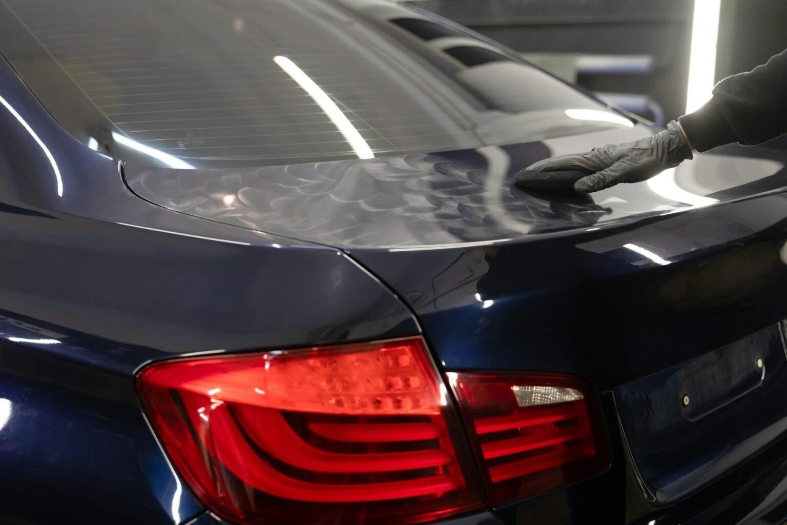Detailing professional applying wax to car body